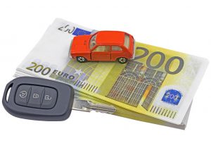 Mini car on euro banknotes and key for automobile on white background